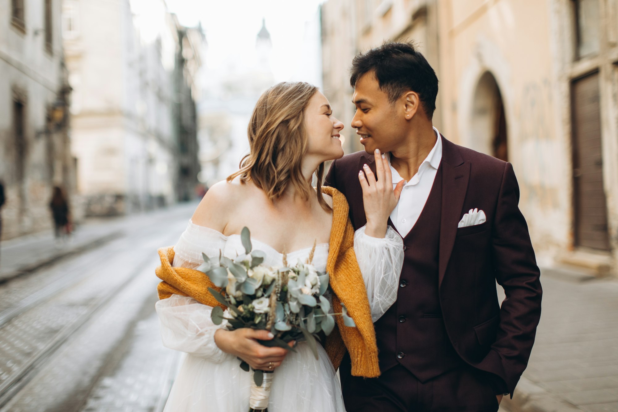 An international wedding couple, a European bride and an Asian groom walk around the city together.